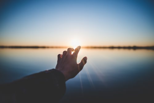 hand reaching toward sunset
